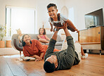 A happy mixed race family of five relaxing in the lounge and being playful together. Loving black family bonding with their son while playing fun games on the floor at home