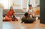 A happy mixed race family of four relaxing in the lounge and being playful together. Loving black family bonding with their kids while playing fun games on the floor at home