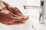 An unknown mixed race father and daughter washing their hands  together in a bathroom at home. Unrecognizable single African American parent teaching his daughter about hygiene