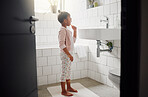 One mixed race adorable little girl brushing her teeth in a bathroom at home. A happy Hispanic child with healthy daily habits to prevent cavities and strengthen enamel