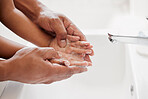 An unknown mixed race father and daughter washing their hands  together in a bathroom at home. Unrecognizable single African American parent teaching his daughter about hygiene