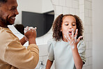 Happy mixed race father and daughter washing their hands  together in a bathroom at home. Single African American parent teaching his daughter about hygiene while having fun and being playful