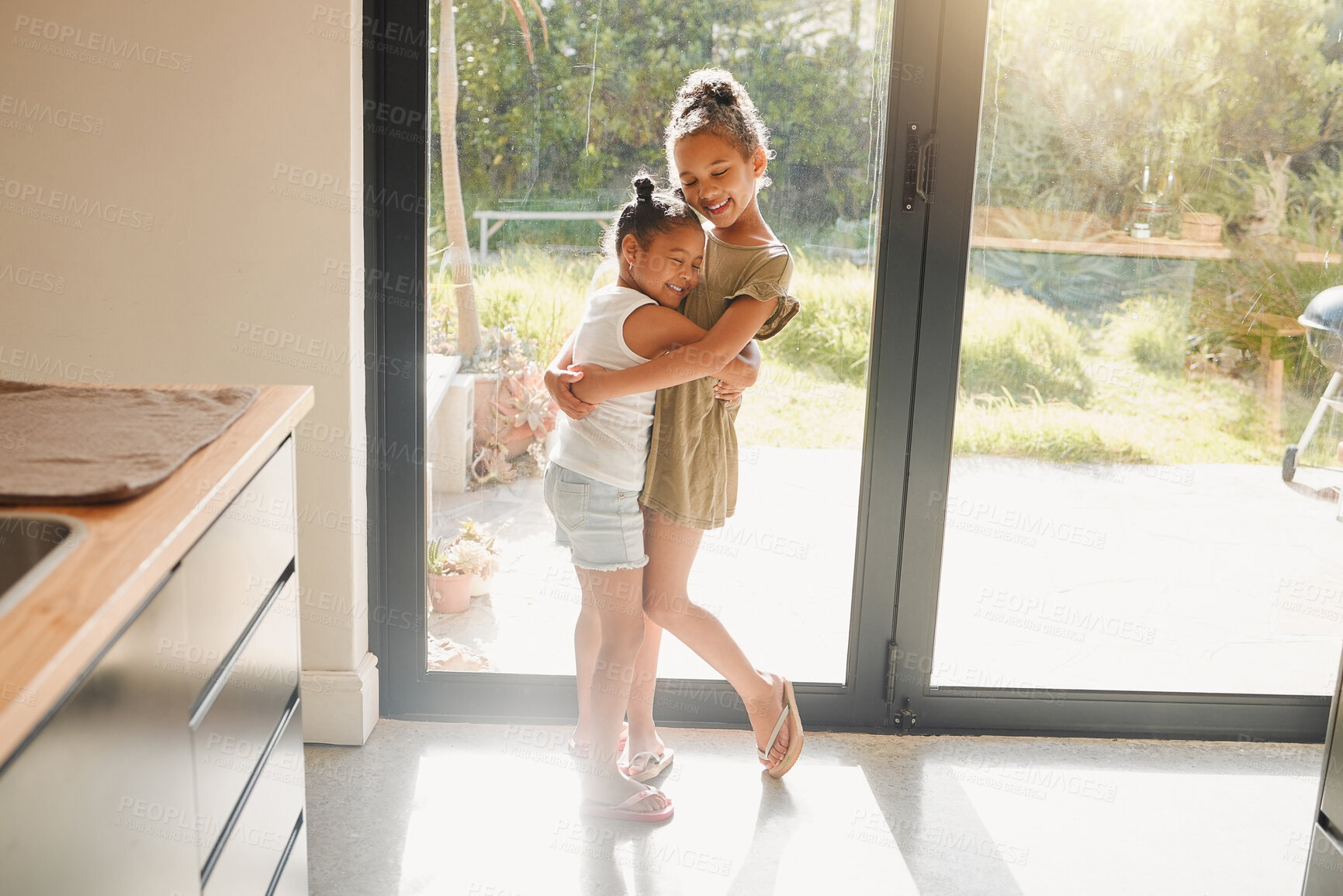 Buy stock photo Love, hug and smile with sisters in house for bonding, support and happiness together. Youth, siblings and care with children embrace  in kitchen of family home for morning, connection and peace