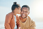 Adorable mixed race girl kisses her father on the cheek while at the beach. Little daughter showing daddy love and affection while he smiles and looks at the camera