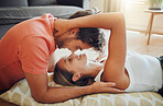 Happy young woman lying on floor while her boyfriend leans over her as they touch noses and looking into each other eyes. Affectionate couple enjoying romantic intimate moment