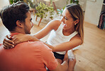 Funny young caucasian couple being playful laughing and having fun while sitting together at home. Young woman sitting on boyfriends lap putting her arms around him while they look at each other