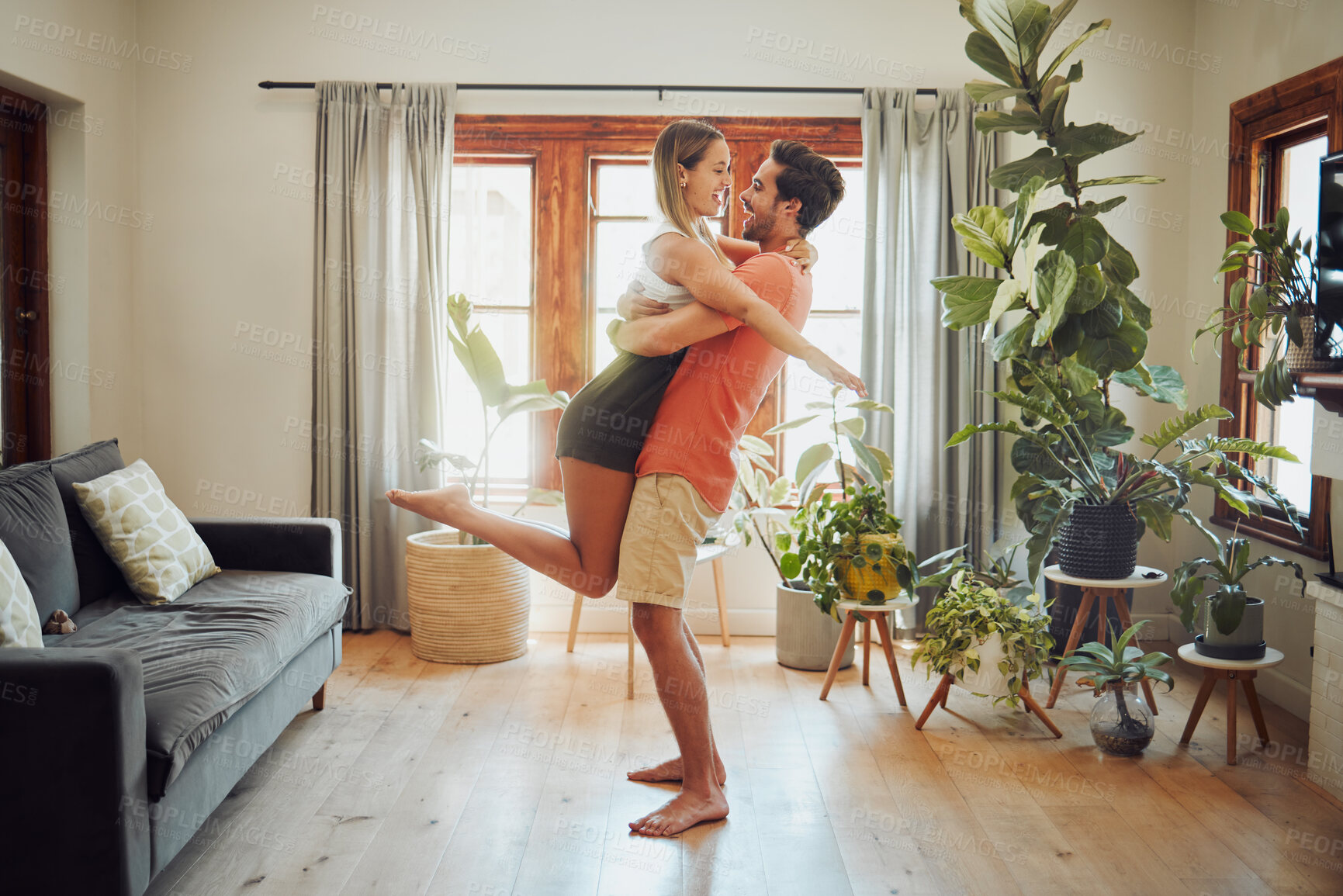 Buy stock photo Couple, romance and lifting woman in home, support wife and love in relationship or fun. People, feet and bonding in apartment for care in marriage, connection and holding for care in partnership