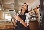 Businesswoman ordering stock on her digital tablet. Business owner using an online digital app in her cafe. Happy boss using a wireless device in her restaurant. Small business owner using 3g app