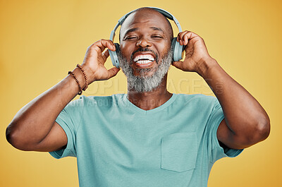 Buy stock photo Black man, headphones and laughing in studio, hearing audio and streaming radio on yellow background. Mature person, energy and funny podcast for humor, technology and online for hip hop playlist