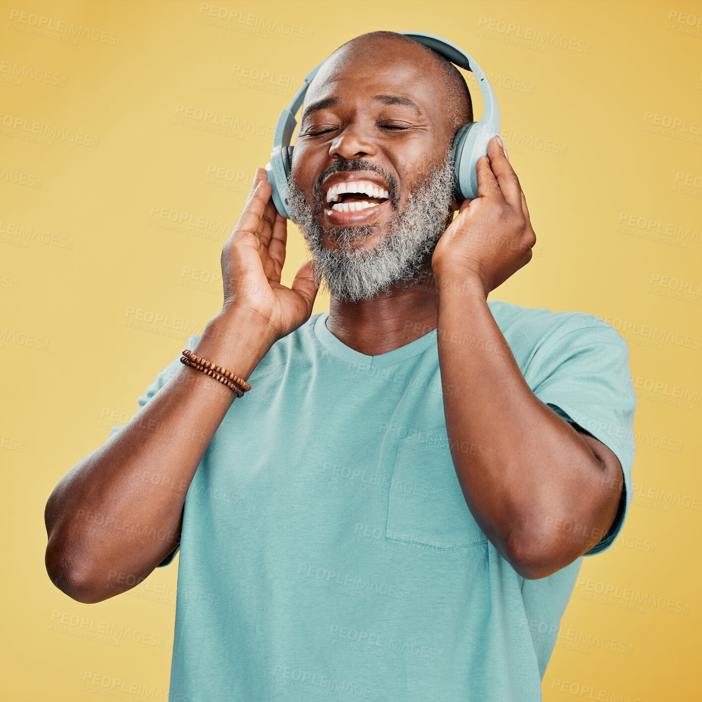 Buy stock photo Black man, headphones and laughing in studio, sound and streaming radio or track on yellow background. Mature person, energy and funny podcast for humor, technology and online for hip hop playlist