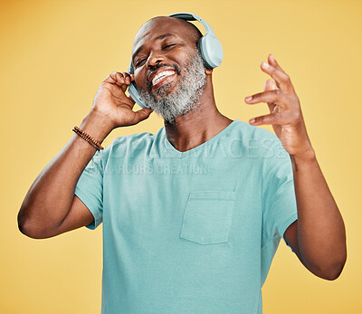 Buy stock photo Black man, headphones and sound in studio, hearing audio and streaming radio on yellow background. Mature person, energy and subscribe for listening to song, tech and online for hip hop playlist