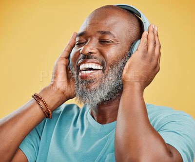 Buy stock photo Black man, headphones and laughing in studio, listening and streaming radio sound on yellow background. Mature person, energy and funny podcast for humor, technology and online for hip hop playlist