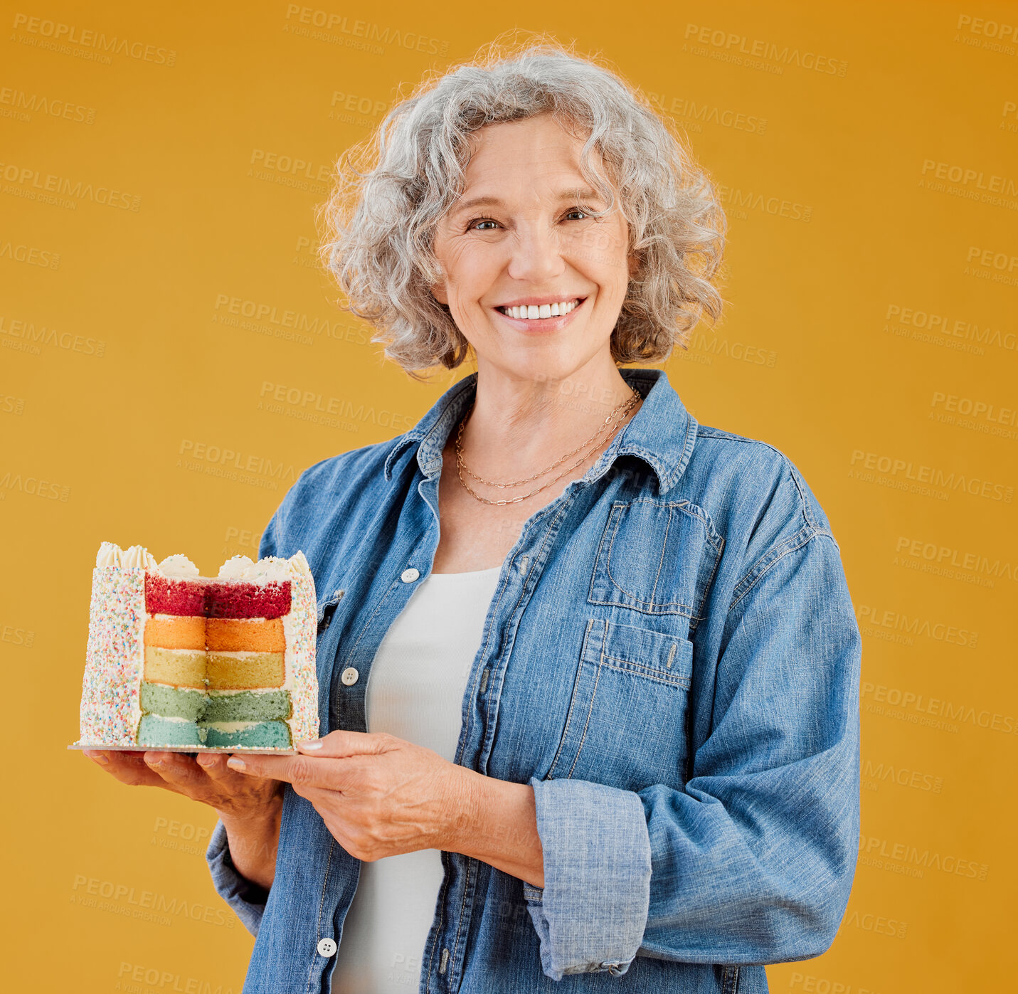 Buy stock photo Birthday, portrait and rainbow cake with old woman in studio isolated on yellow background for party. Celebration, milestone and fondant with proud senior person holding desert for happy event