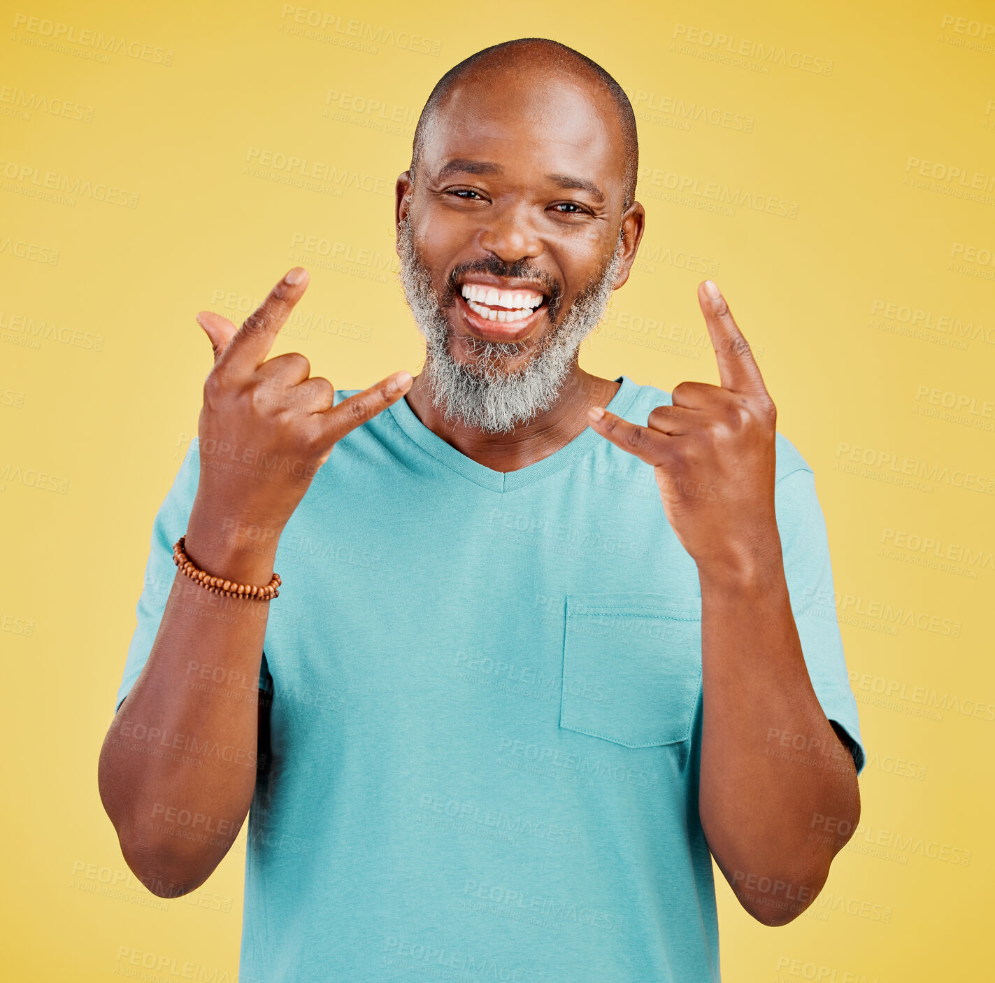 Buy stock photo Horns hand gesture, portrait and senior black man in studio isolated on yellow background for celebration. Face, rock n roll and smile of happy mature person with emoji for expression or grunge