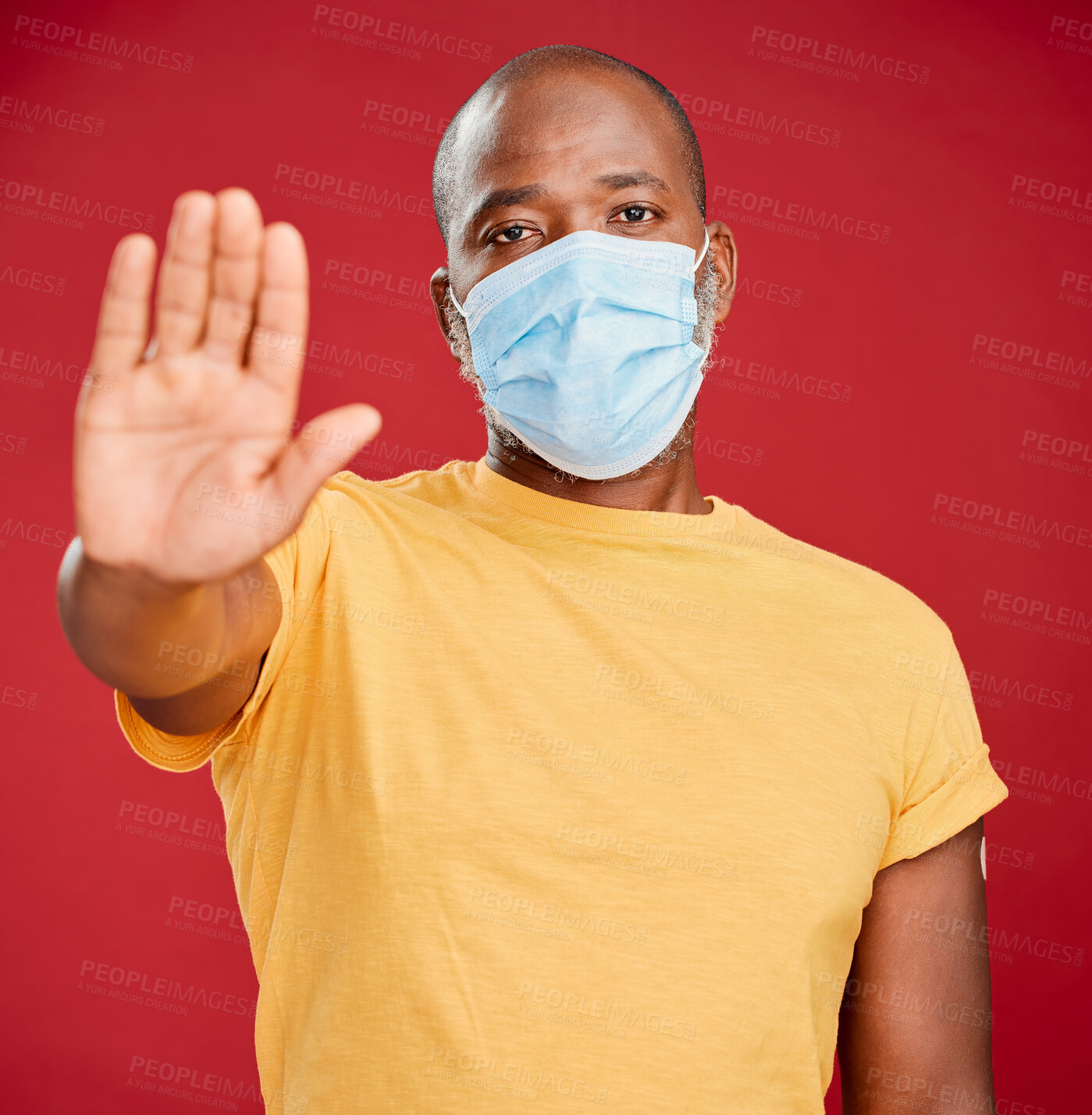 Buy stock photo Black man, portrait and mask with hand for stop, halt or no entry on a red studio background. African, male person or model with face protection, gesture or danger for caution, warning or alert sign