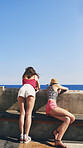 Two friends enjoying view of ocean in Italy. Rear view of fashion girl friends looking at view of sea on travel adventure vacation