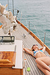 Young woman relaxing on holiday cruise on boat sunbathing in bikini. Woman in bikini lying on a yacht sunbathing enjoying holiday cruise