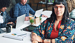 Portrait of a young powerful businesswoman in a meeting with her staff. A focused young businesswoman sitting at her desk before a meeting with a diverse group of staff.