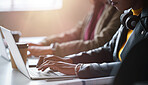 A focused businesswoman typing on her laptop while sitting next to her coworker. Closeup of an african american businesswoman working on her laptop in an office with her colleague