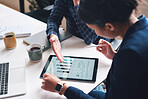 A businesswoman reading financial information on a digital tablet during a meeting with her colleague. Two businesspeople planning their financial strategy using a digital tablet in a meeting