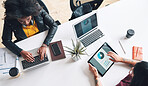 Two businesswoman working together using digital tablets and laptops from above. Two businesswoman planning together during a meeting using a digital tablet and laptop. Two colleagues using devices