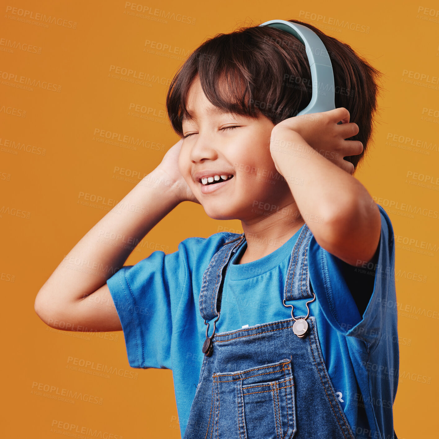 Buy stock photo Asian boy, kid and headphones with smile, listening to music and happiness on yellow studio background. Comfortable, radio and model with headset, audio and child with technology and noise cancelling