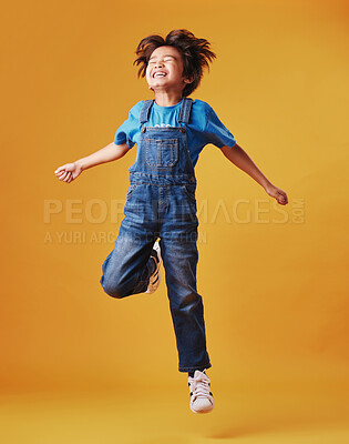 Buy stock photo Freedom, jump and smile with Asian boy on yellow background, isolated in studio for growth. Action, excited or fashion and happy child with energy in air having fun for child development or future