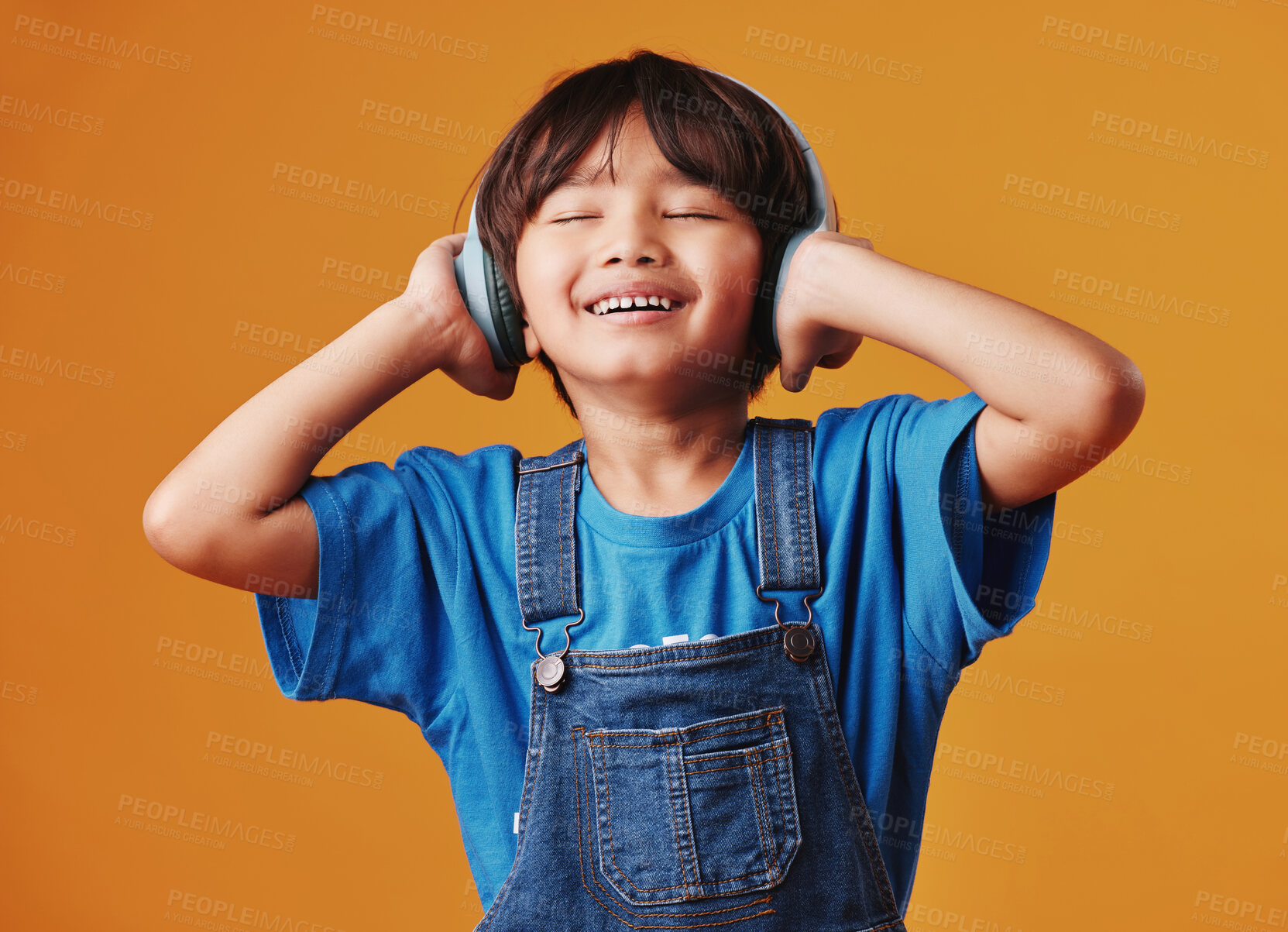 Buy stock photo Asian boy, child and headphones with sound, listening to music and happiness on yellow studio background. Live streaming, radio and model with headset, audio and smile with tech, kid and wellness