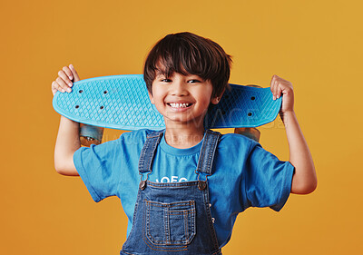 Buy stock photo Japanese boy, studio background and happy with skateboard for sports or recreation in Japan. Young person, skater and smile on portrait in confidence for fashion, style and outfit for hobby or growth