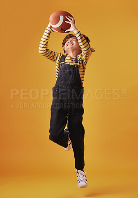 Buy stock photo Child, jump and catch football for sport, fun game and training for exercise isolated on studio background. Happy kid, air and boy with ball with energy for play, RUGBY and fitness for competition