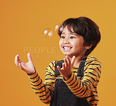 Buy stock photo Studio, child and playing with bubbles, fun and sensory experience for boy, relax and happy with game. Smile, youth and kid with motor skills, liquid and popping of soap, joy and visual appeal