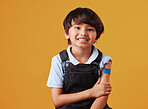 Portrait of a smiling happy mixed race showing his bandaid and posing against an orange copyspace background after getting the Covid vaccine injection. Happy child after getting his shots