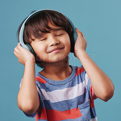 Buy stock photo Asian boy, kid and headphones with audio, listening to music and happiness on blue studio background. Live streaming, radio and model with headset, sound and calm with child, adhd and wellness