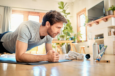 Buy stock photo One fit young caucasian man doing elbow plank hold bodyweight exercise while training with online tutorial on digital tablet at home. Focused guy gaining muscle, increase endurance, enhance upper body and core strength during workout