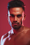 Closeup portrait of one fit and strong handsome mixed race man isolated against a red background in a studio and posing shirtless. Headshot of serious and focused hispanic man looking determined