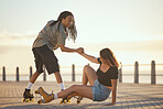 Beach, falling and couple roller skating at the in summer for a fun and healthy cardio activity at sea together. Friends love to skate and exercise on the sidewalk as young girl falls on the ground