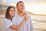 Affectionate young mixed race couple sharing an intimate moment on the beach. Happy husband and smiling wife enjoying a summer day by the sea. They love spending time together on the coast at sunset