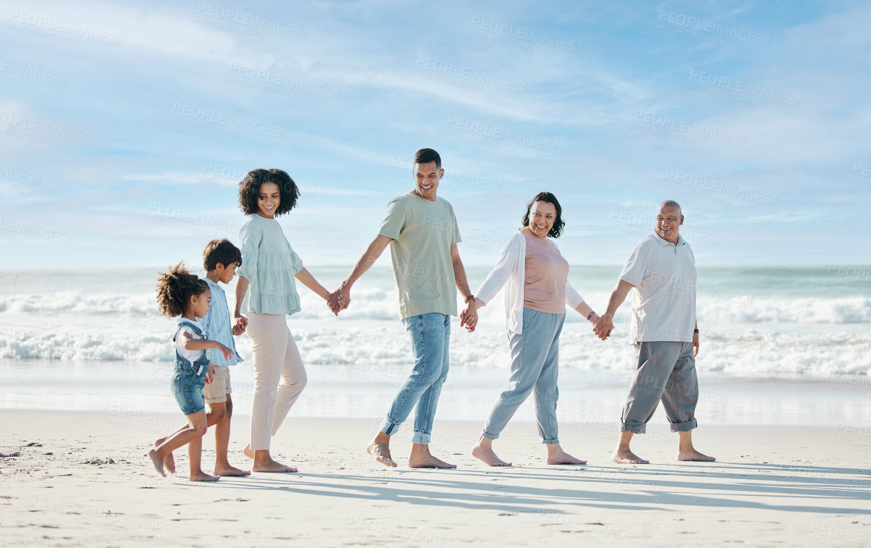 Buy stock photo Summer, beach and a family holding hands while walking on the sand by the ocean or sea together. Grandparents, parents and children outdoor in nature for travel, vacation or holiday on the coast