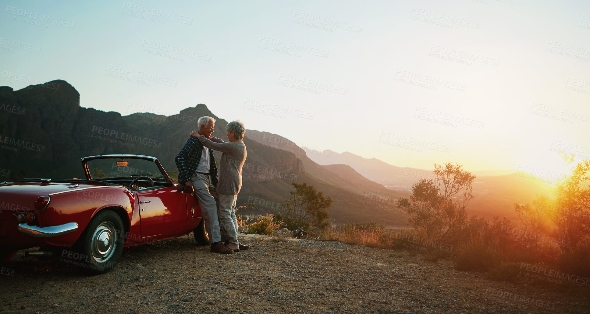 Buy stock photo Shot of an affectionate senior couple enjoying the sunset during a roadtrip