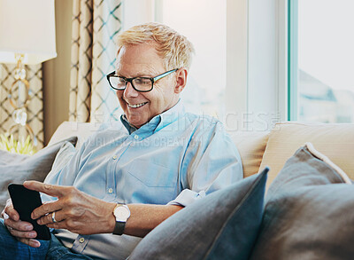 Buy stock photo Shot of a mature man using a phone at home on the sofa