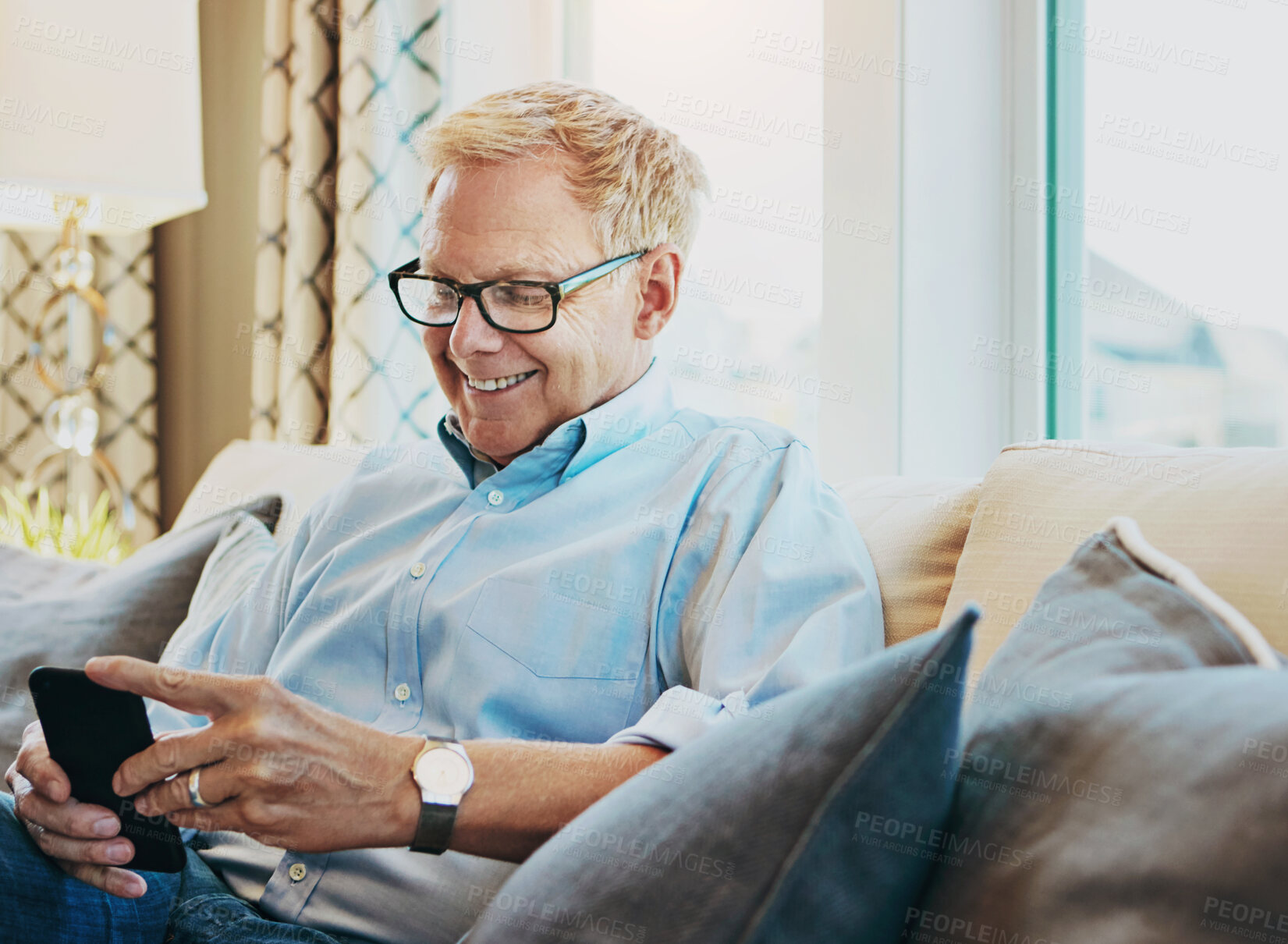 Buy stock photo Shot of a mature man using a phone at home on the sofa