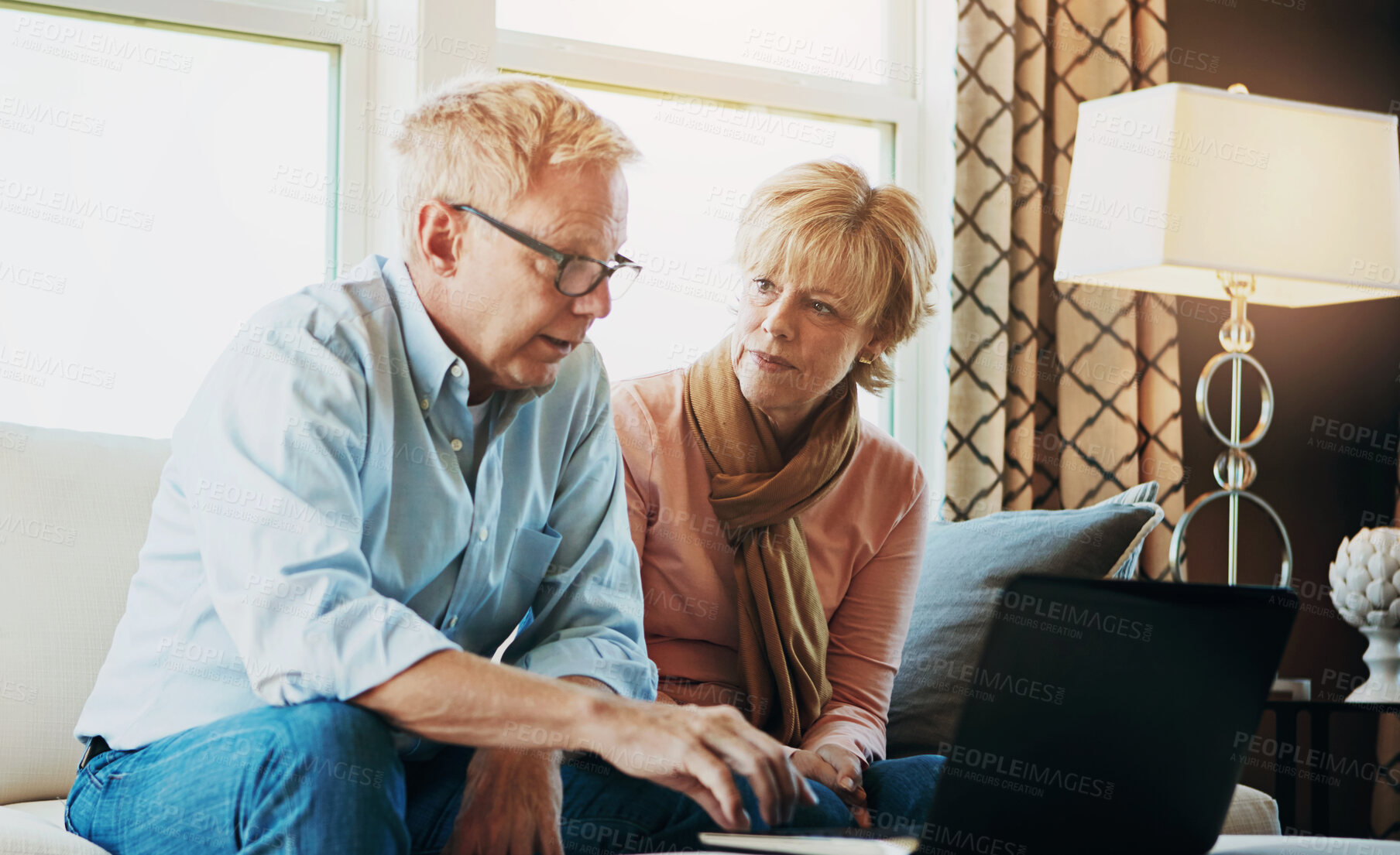 Buy stock photo Shot of a mature couple using a laptop together at home on the sofa