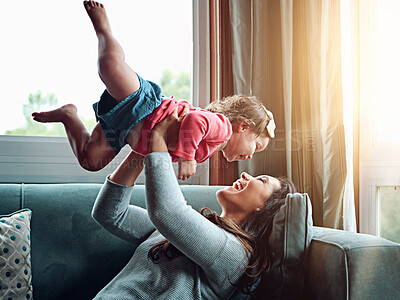 Buy stock photo Mom, happy and lifting girl on sofa in home living room and relax, bonding and quality time together or mother, love and family happiness. Child, mommy and playing game on couch in house with smile