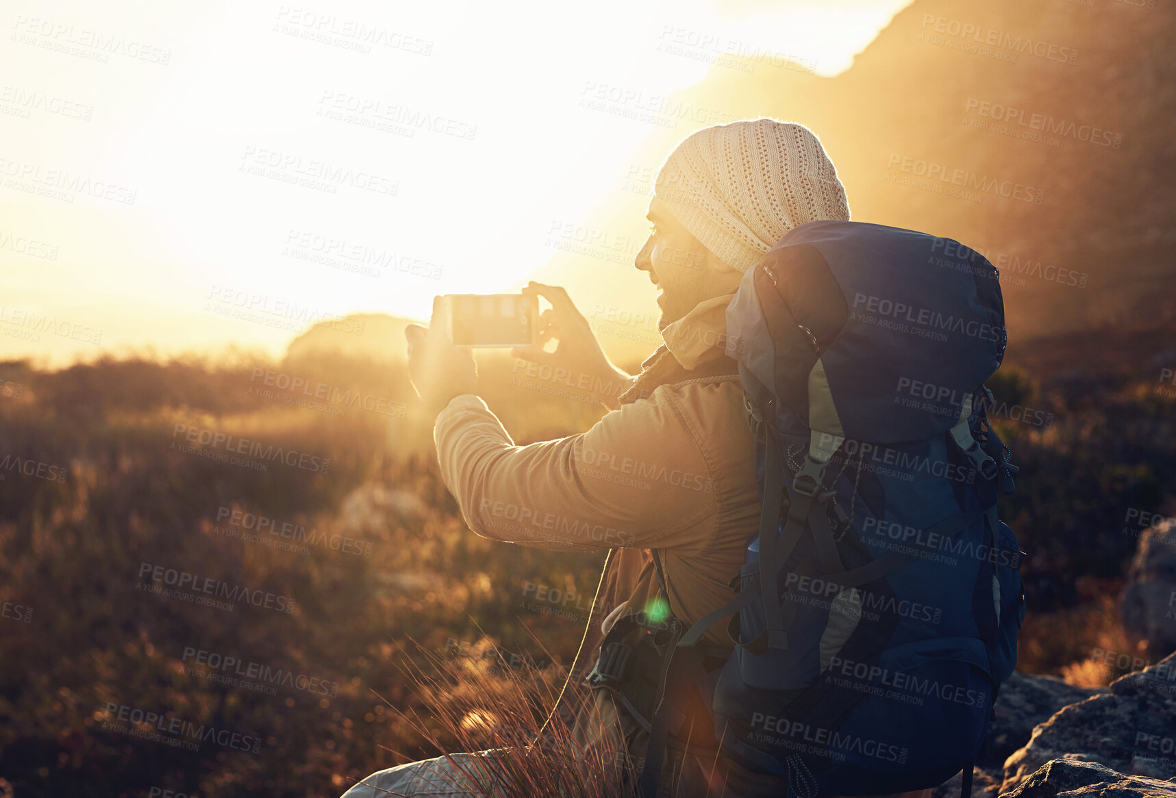 Buy stock photo Flare, hiking and photograph with man in mountains for break, memory or scenic view of nature. Earth, phone camera and rest at sunset with happy person outdoor for adventure, fresh air or journey