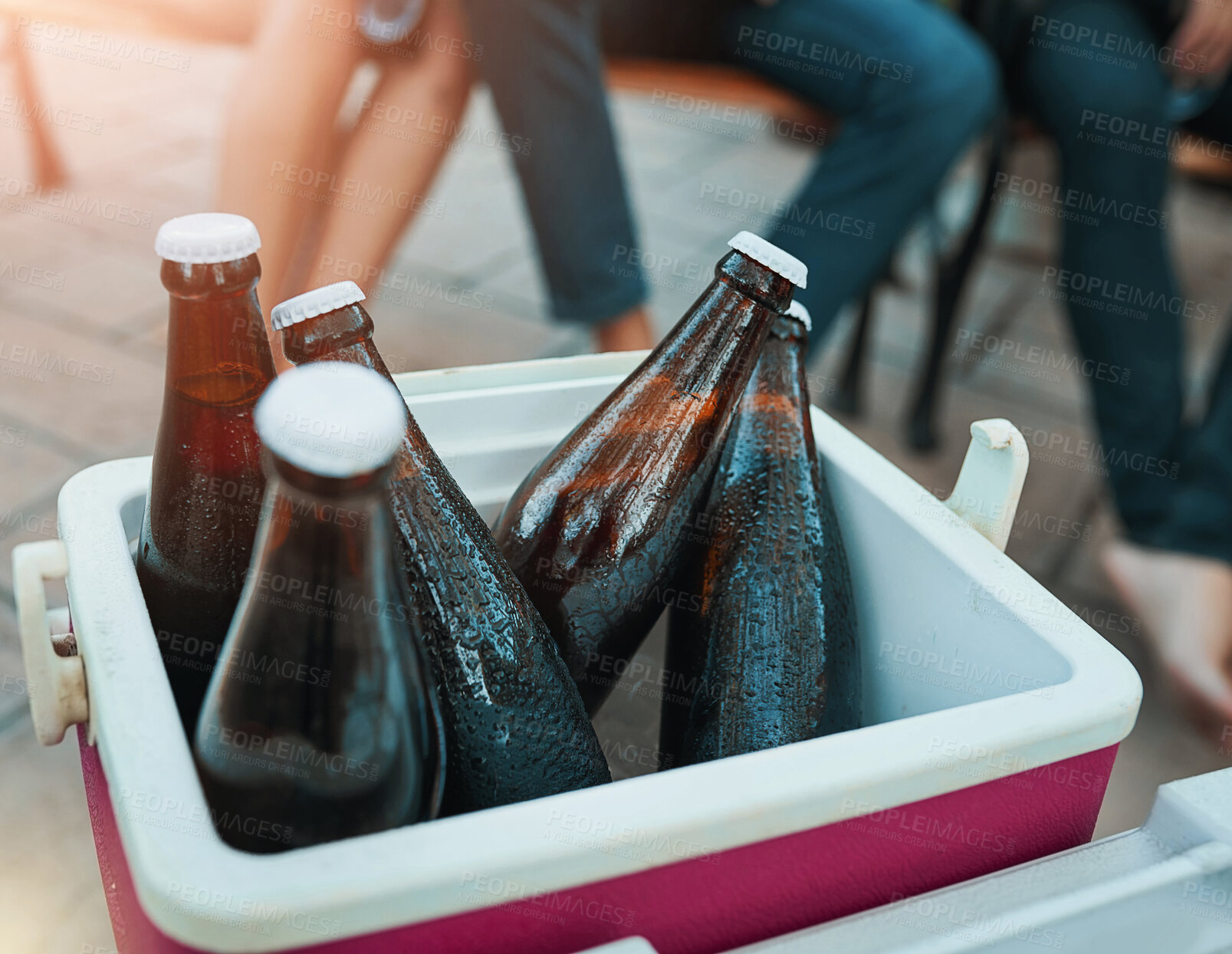 Buy stock photo Friends, drinks and outdoor cooler box for party or celebration and holiday in summer or light leak of sunset. People legs with cold beverage, beer or alcohol bottle in ice for relax hangout at home