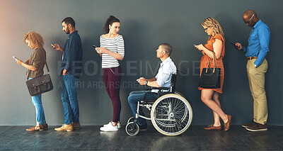 Buy stock photo Shot of a group of people standing in a row behind each other while using their phones