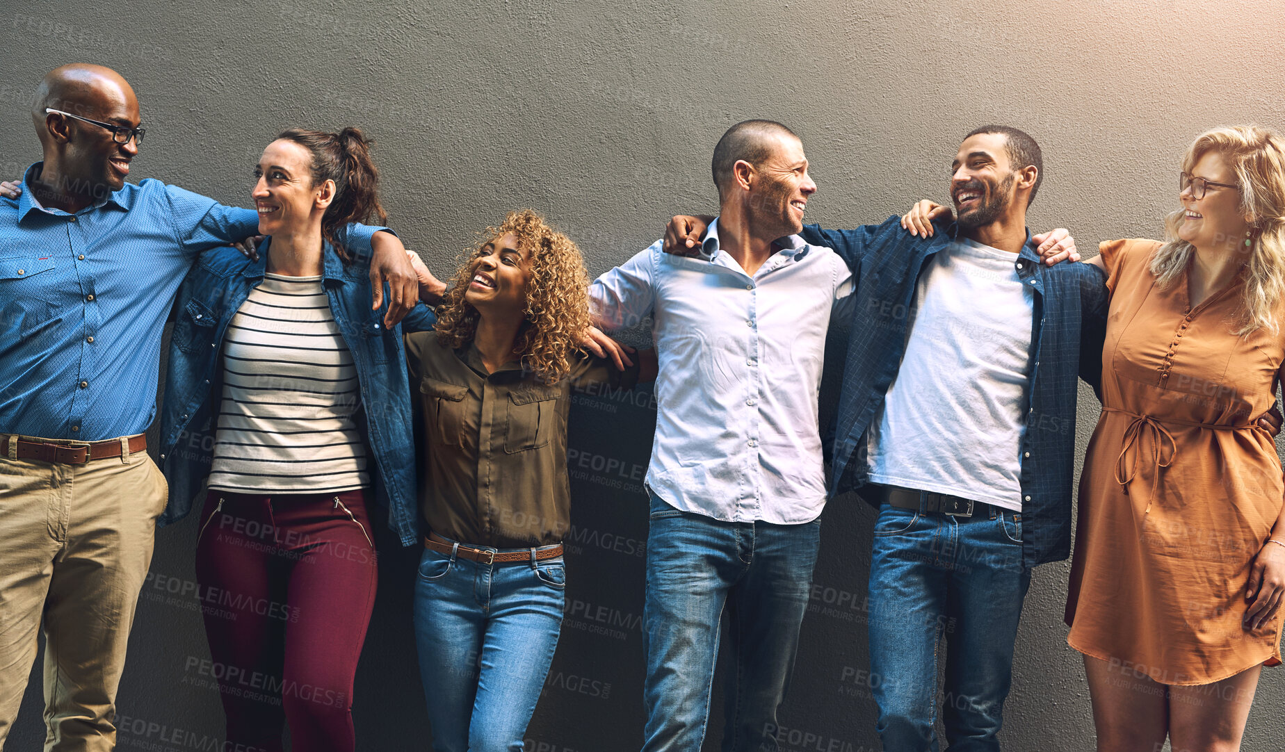 Buy stock photo Shot of a group cheerful friends holding each other while posing for a photo outside of a building