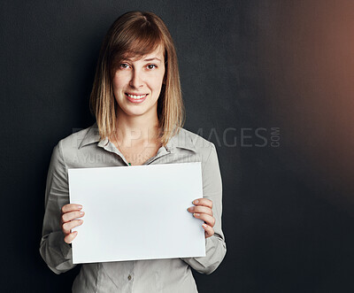 Buy stock photo Portrait, poster and mock up with a woman in studio on a dark background holding a blank sign. Announcement, information or advertising with a female brand ambassador showing empty space on a placard