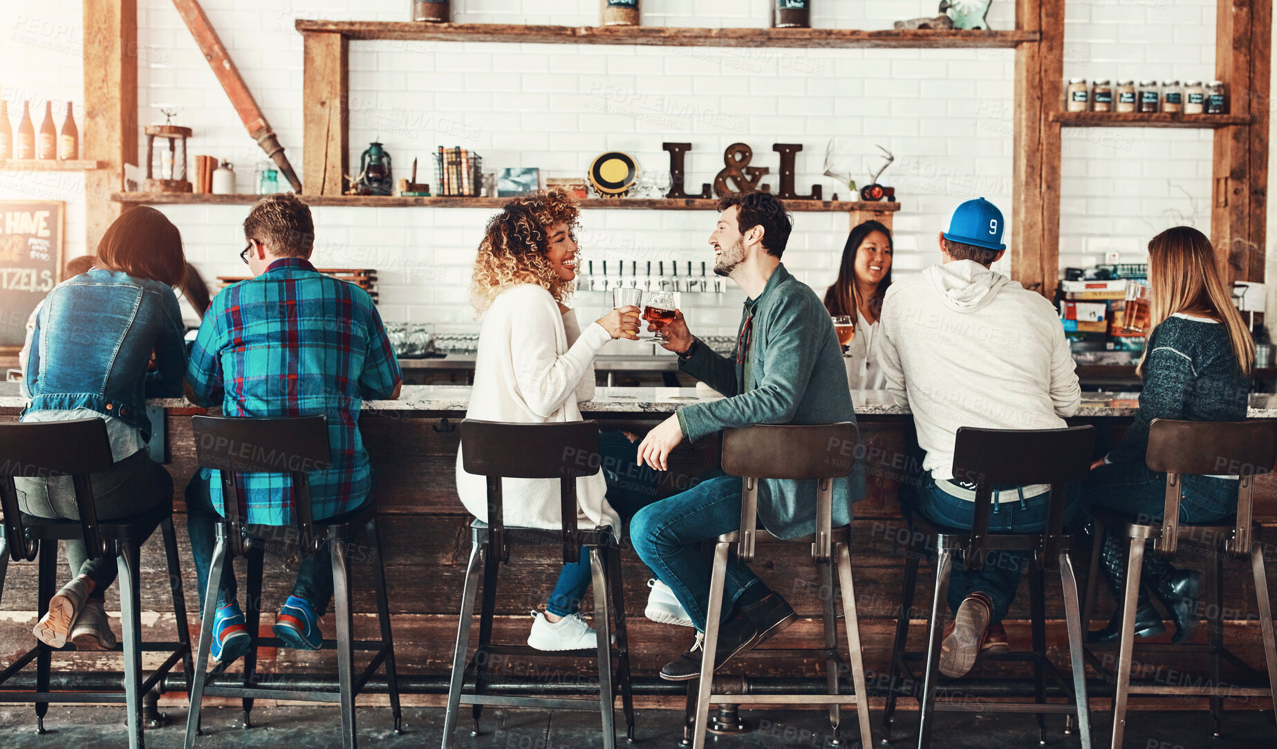 Buy stock photo Shot of young people enjoying a drink at a bar