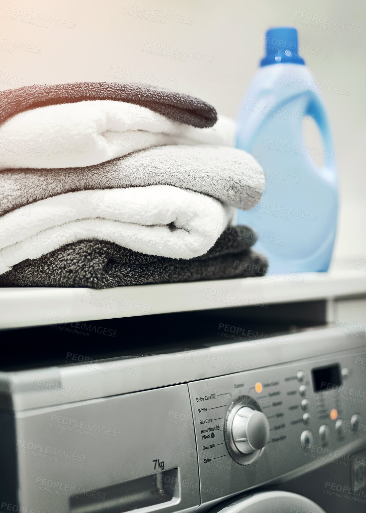 Buy stock photo Washing machine with stacked, folded towels and detergent on a countertop inside a scullery room at home. Clean clothes after washing, cleaning, drying. Using household equipment for hygiene.